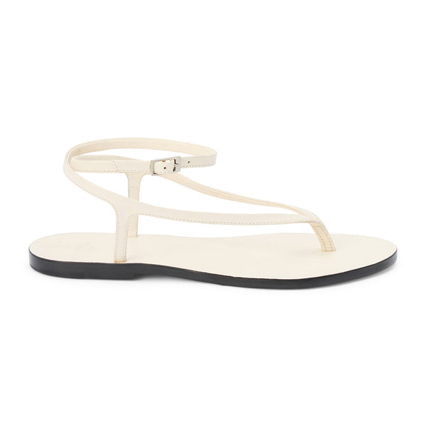 Ivory leather thong sandal with a minimalist strappy design and adjustable ankle buckle. A sleek and versatile style for effortless warm-weather dressing.