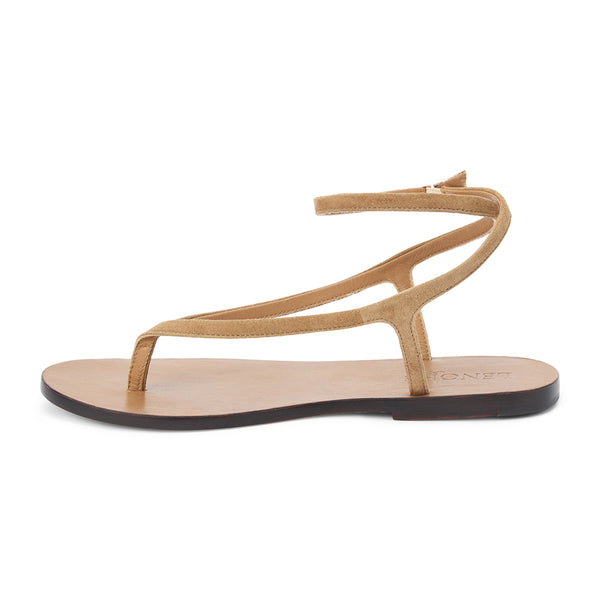 Light brown suede thong sandal with a minimalist strappy design and adjustable ankle buckle. A sleek and versatile style for effortless warm-weather dressing.