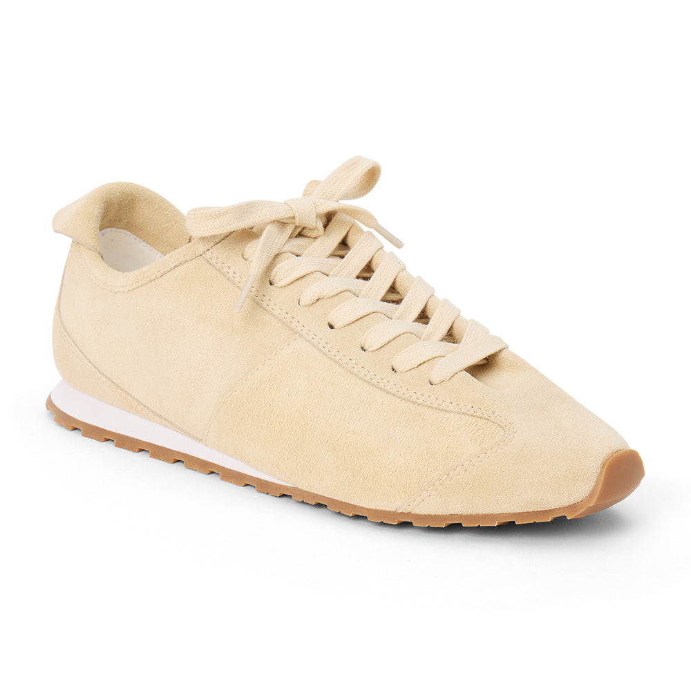 Ivory suede trainer with tonal laces, stitched paneling, a low-profile silhouette, white midsole, and gum outsole shown on a white background.