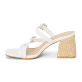 White faux leather sandal with adjustable buckle straps, open square toe, raffia-wrapped block heel, and slip-on design, shown on a white background.