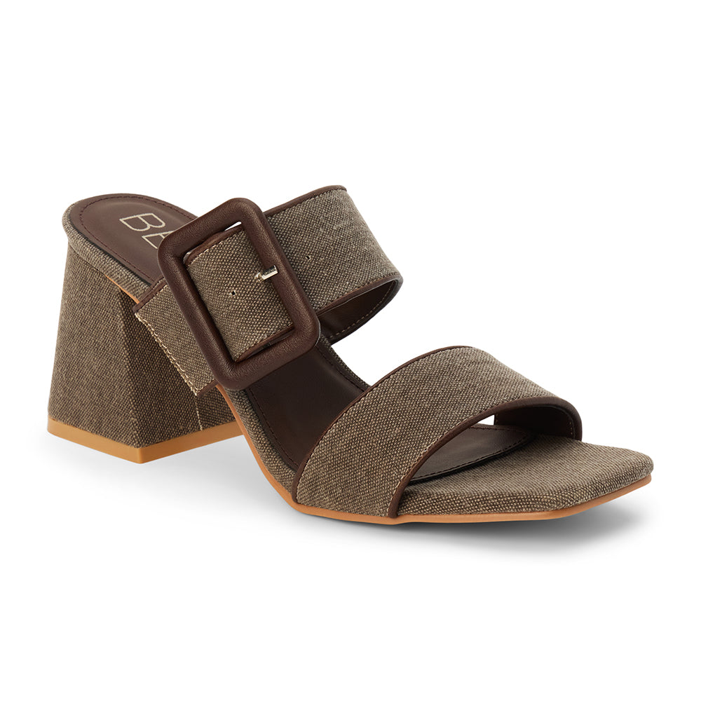 Chocolate textile heeled sandal with a wide textured strap, oversized buckle detail, square toe, and block heel, shown on a white background.