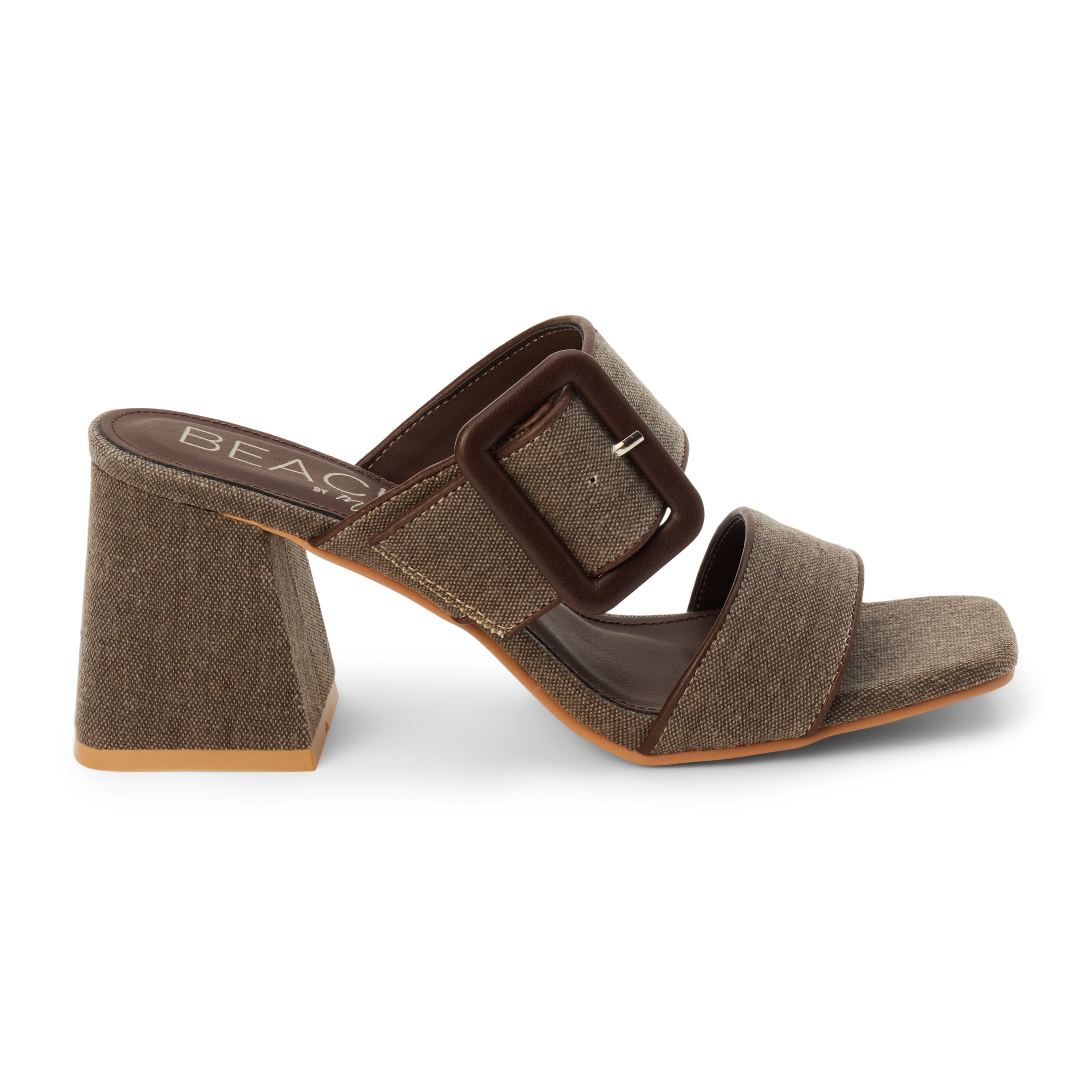 Chocolate textile heeled sandal with a wide textured strap, oversized buckle detail, square toe, and block heel, shown on a white background.