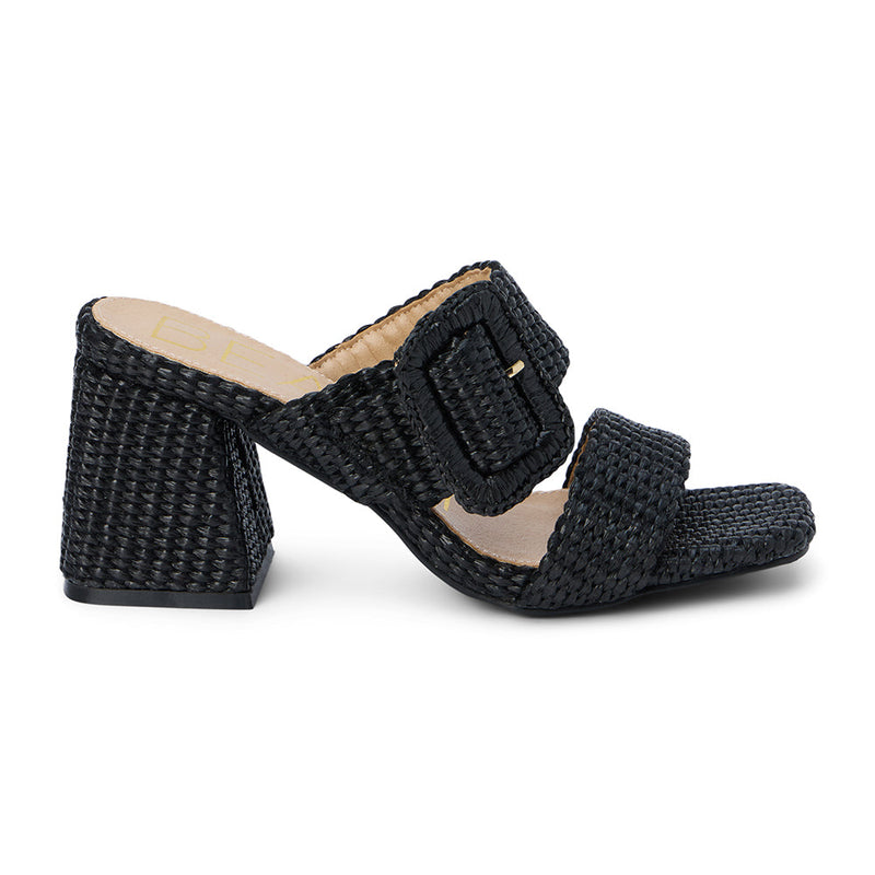 Lucy Heeled Sandal – Beach By Matisse – Black woven heeled sandals with a bold oversized buckle detail, double strap design, and flared block heel. A playful yet polished statement piece perfect for sun-soaked days.