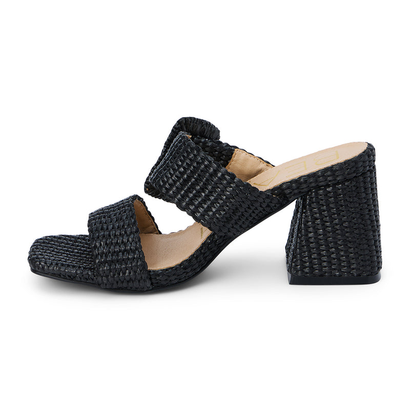 Lucy Heeled Sandal – Beach By Matisse – Black woven heeled sandals with a bold oversized buckle detail, double strap design, and flared block heel. A playful yet polished statement piece perfect for sun-soaked days.