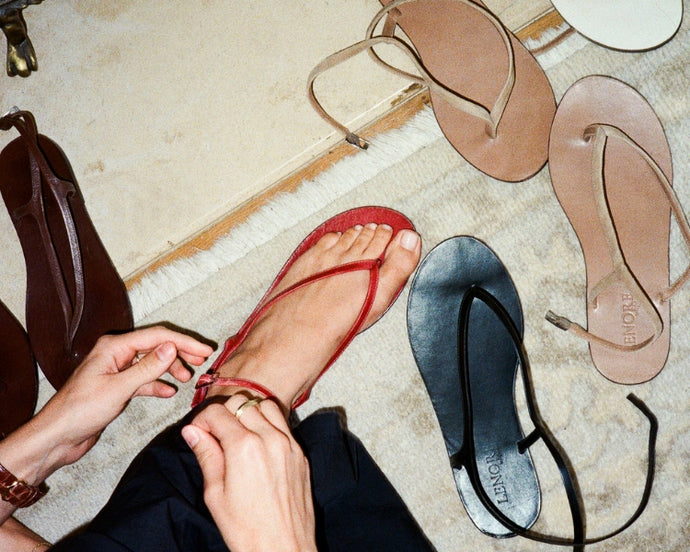 Person trying on sandals with additional shoes in the background.