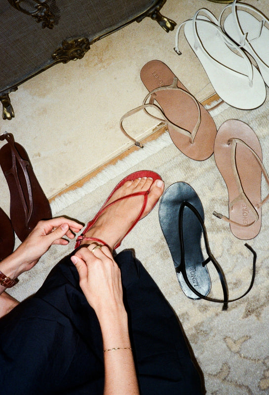 Person trying on sandals with additional shoes in the background.