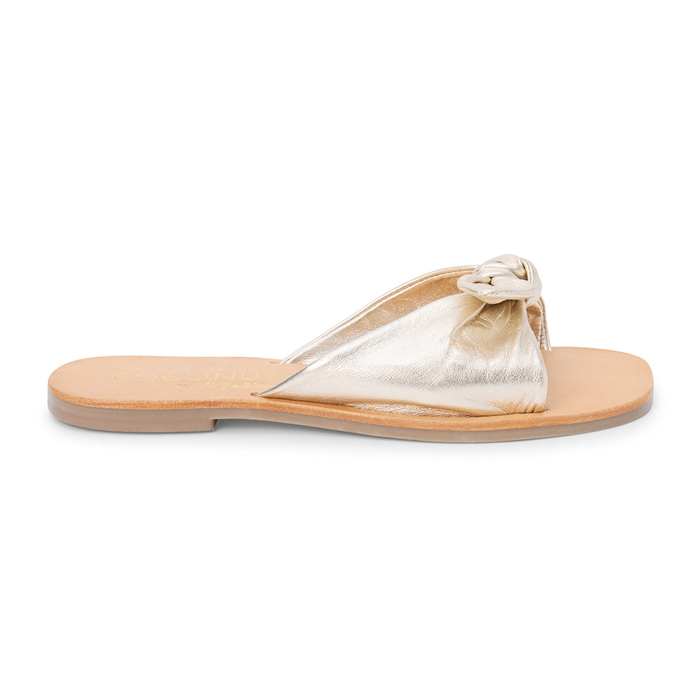 Gold leather slide sandal with knotted strap and open toe shown on a white background.