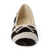 Ivory and dark brown zebra-print cow hair ballet flat with an ivory bow, rounded toe, tonal trim, and low heel shown on a white background.