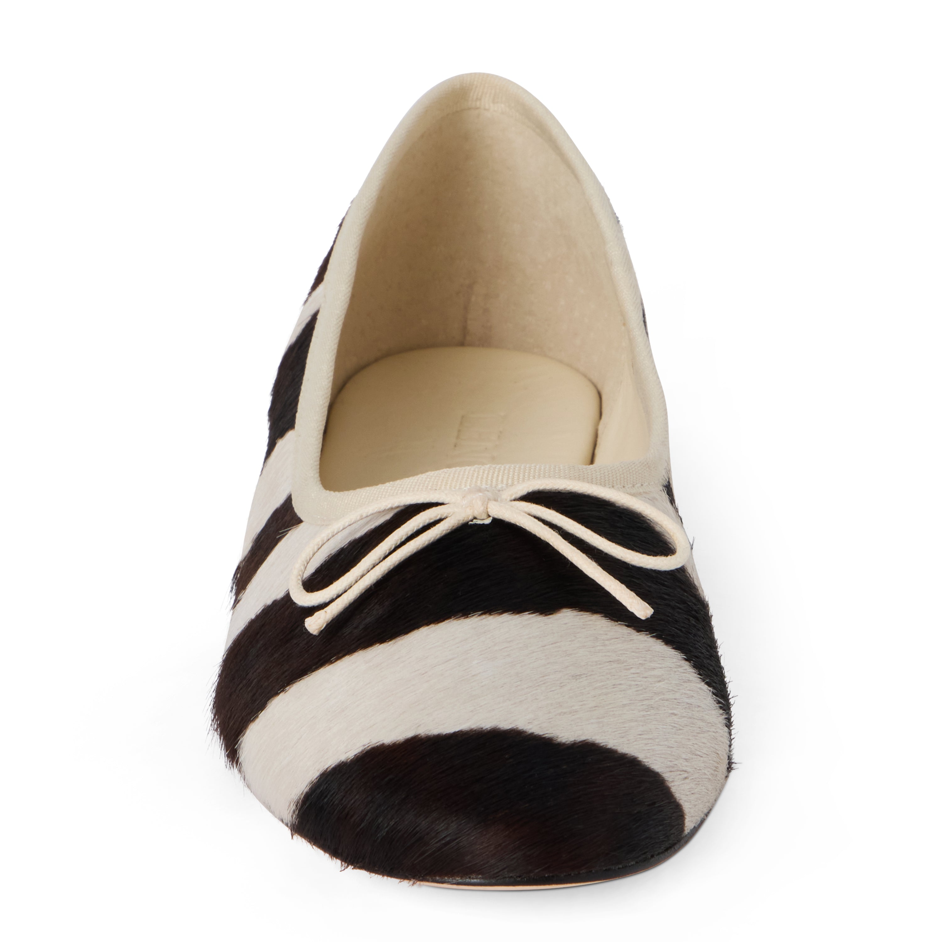 Ivory and dark brown zebra-print cow hair ballet flat with an ivory bow, rounded toe, tonal trim, and low heel shown on a white background.