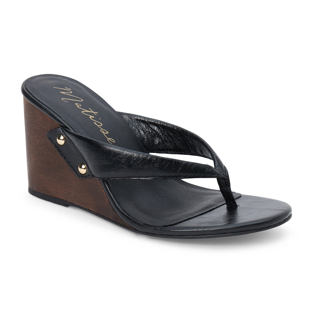 Black leather wedge sandal with thong strap and wooden heel, shown on a white background.