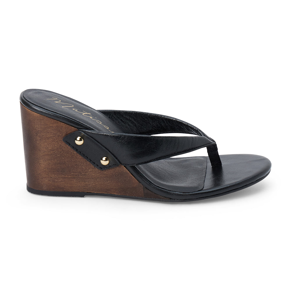 Black leather wedge sandal with thong strap and wooden heel, shown on a white background.