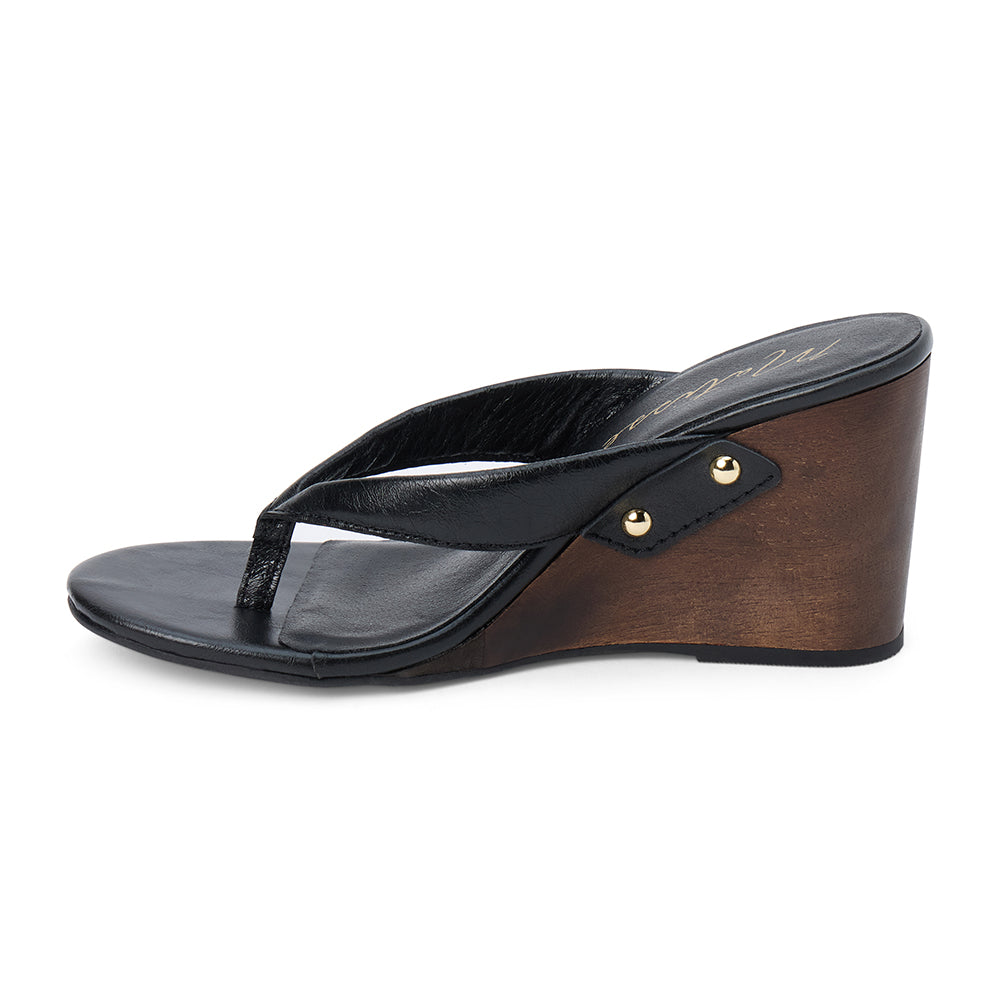 Black leather wedge sandal with thong strap and wooden heel, shown on a white background.