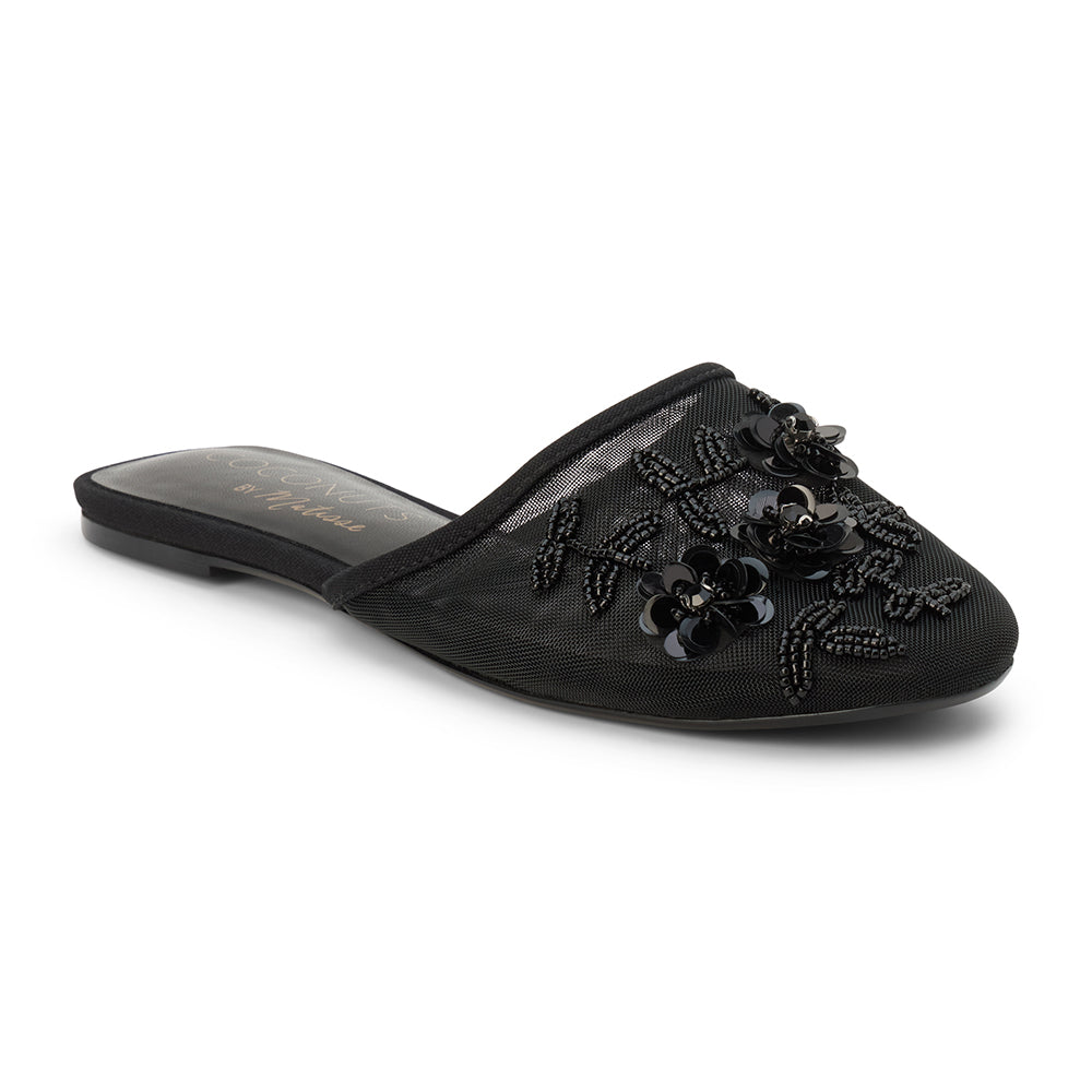 Black mesh mule with floral embellishments, slip-on design, low flat sole, and pointed toe, shown on a white background.