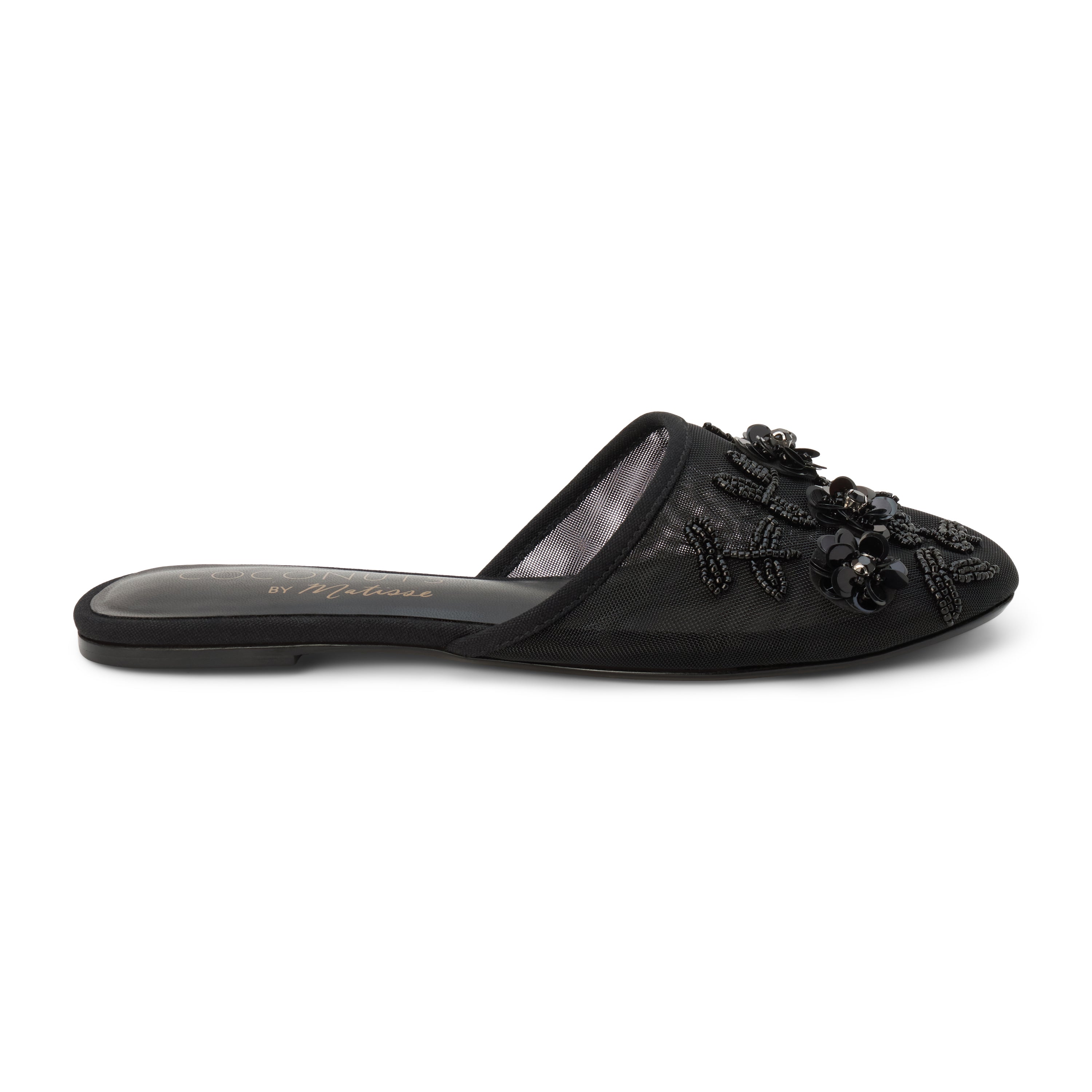 Black mesh mule with floral embellishments, slip-on design, low flat sole, and pointed toe, shown on a white background.