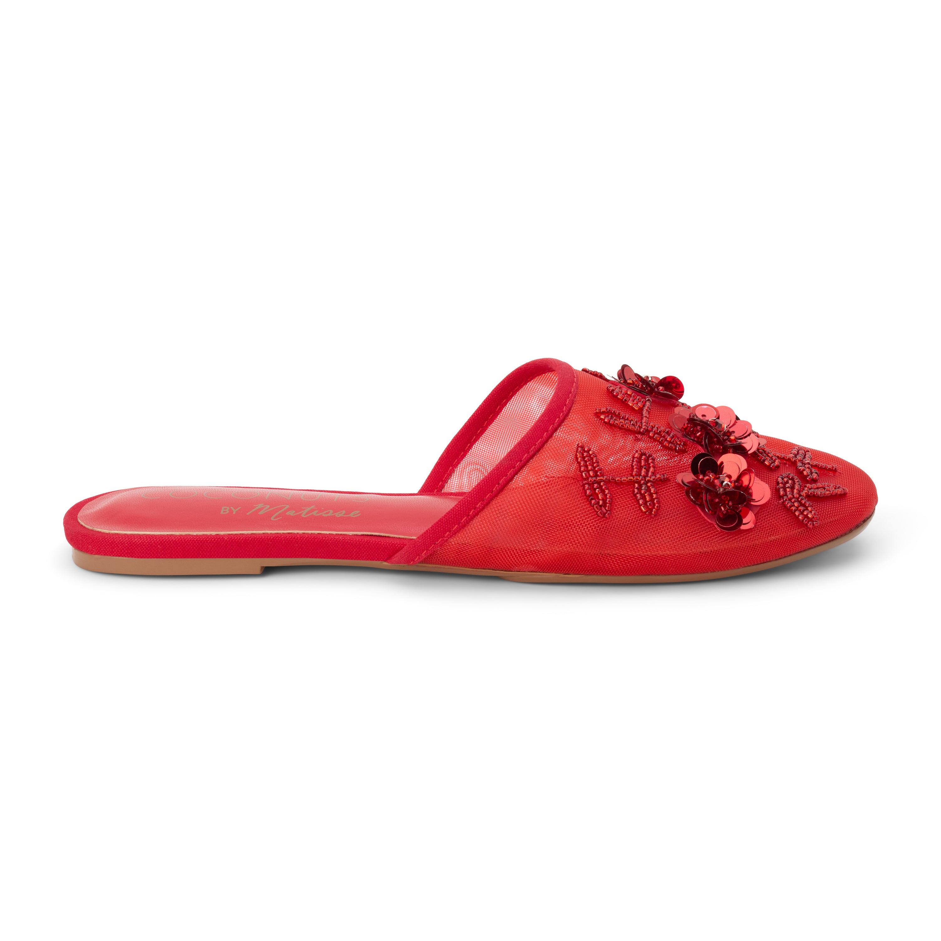 Red mesh mule with floral embellishments, slip-on silhouette, low flat sole, and pointed toe, shown on a white background.