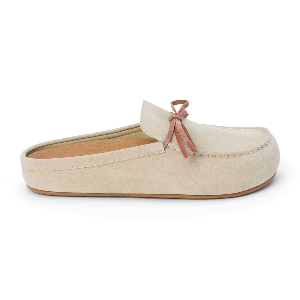 Tan suede clog with a moc-style apron toe, decorative leather bow, and backless silhouette shown on a white background.