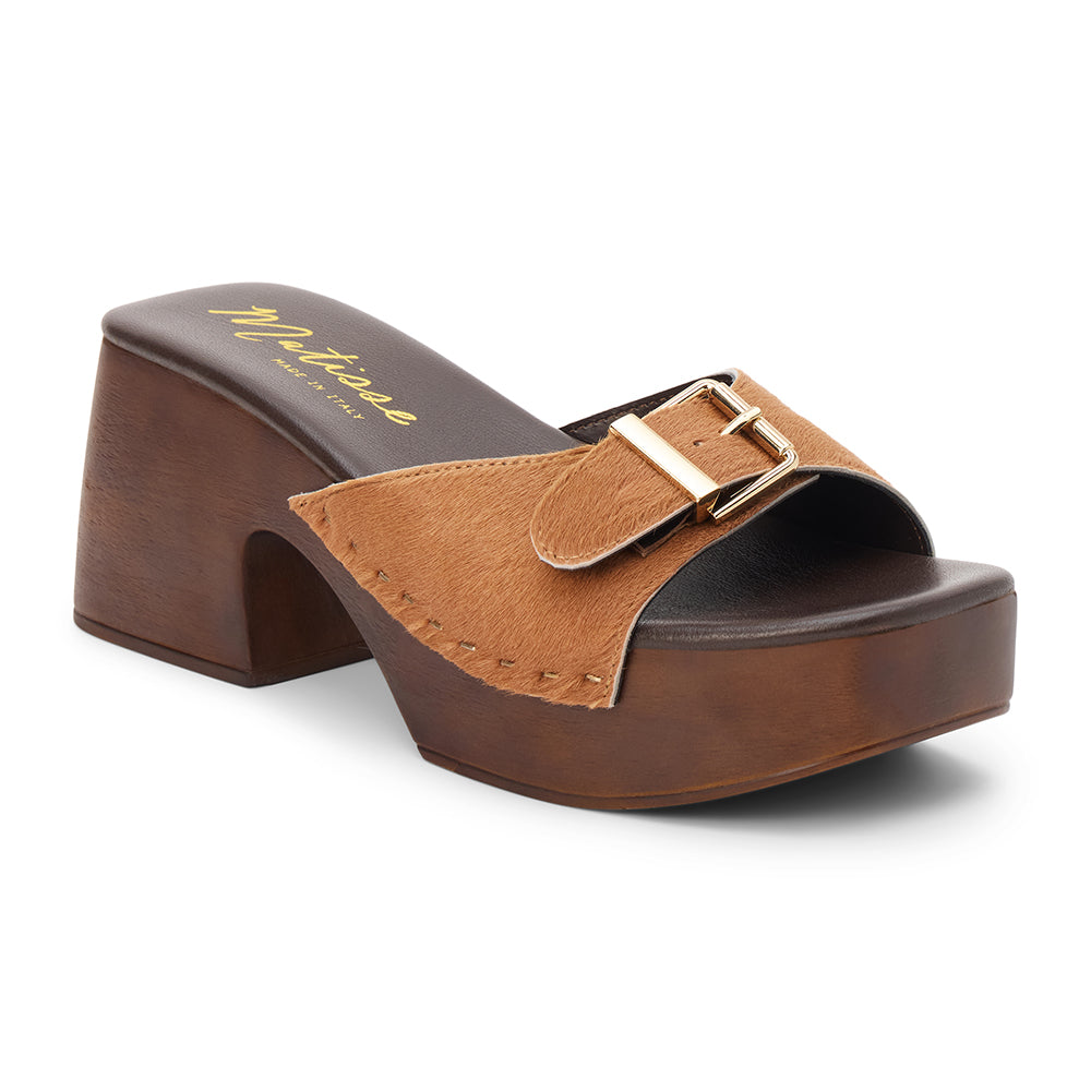 Tan cow hair platform sandal with wide buckle strap and wooden block heel, shown on a white background.