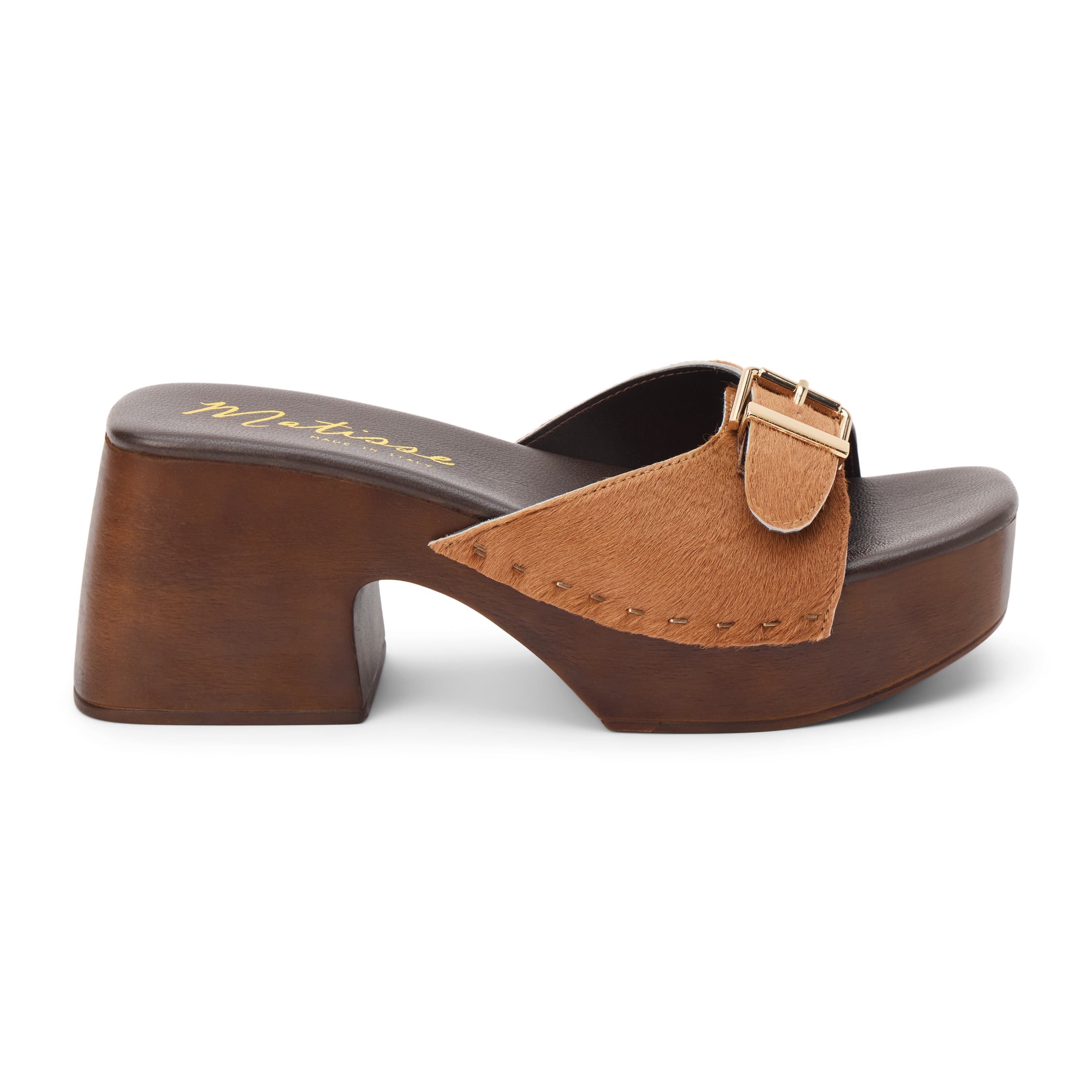 Tan cow hair platform sandal with wide buckle strap and wooden block heel, shown on a white background.