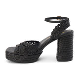 Black raffia platform sandal with woven straps, ankle buckle, and block heel, shown on a white background.