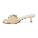 Beige vegan faux leather heeled sandal with knotted bow detail and slim heel, shown on a white background.