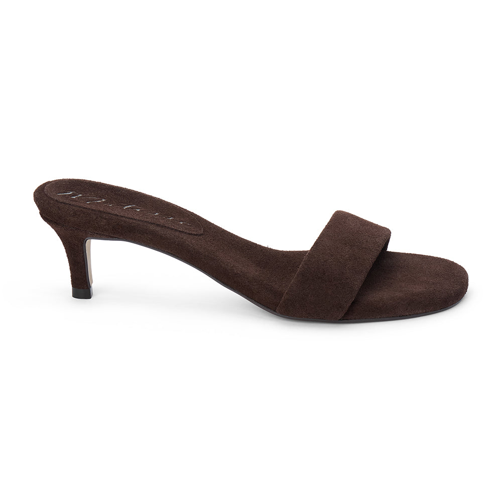 Brown suede slide sandal with wide strap and low kitten heel, shown on a white background.