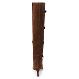 Brown suede knee-high boot with four silver-tone buckle accents, a pointed toe, and slim brown kitten heel shown on a white background.