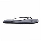 Black leather flat thong sandal with slim knotted straps and square toe, shown on a white background.
