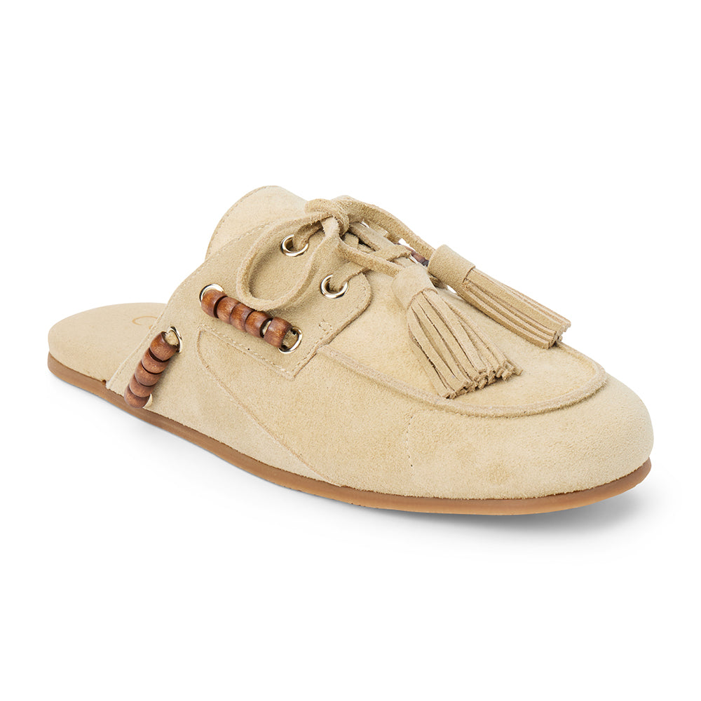 Tan suede mule with an open back, moc-toe stitching, lace-up tassels, wood bead accents, and a flat sole shown on a white background.