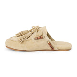 Tan suede mule with an open back, moc-toe stitching, lace-up tassels, wood bead accents, and a flat sole shown on a white background.