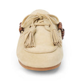Tan suede mule with an open back, moc-toe stitching, lace-up tassels, wood bead accents, and a flat sole shown on a white background.