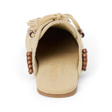 Tan suede mule with an open back, moc-toe stitching, lace-up tassels, wood bead accents, and a flat sole shown on a white background.
