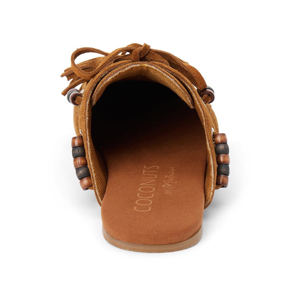 Brown suede mule with an open back, moc-toe stitching, lace-up tassels, contrasting wood bead accents, and a flat sole shown on a white background.