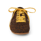 Vegan brown leopard-print faux suede sneaker with brown overlays, contrasting yellow laces, a rounded toe, and flat sole shown on a white background.