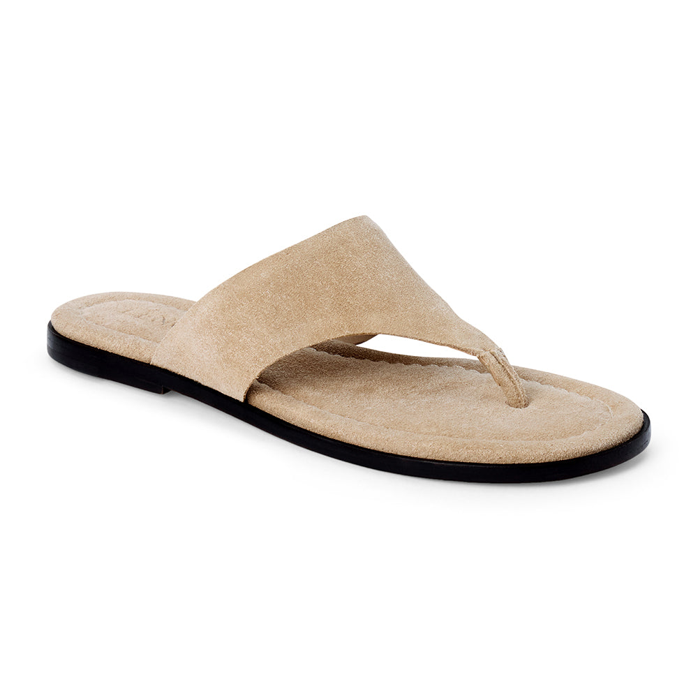 Sand beige suede flat thong sandal with wide strap and cushioned footbed, shown on a white background.