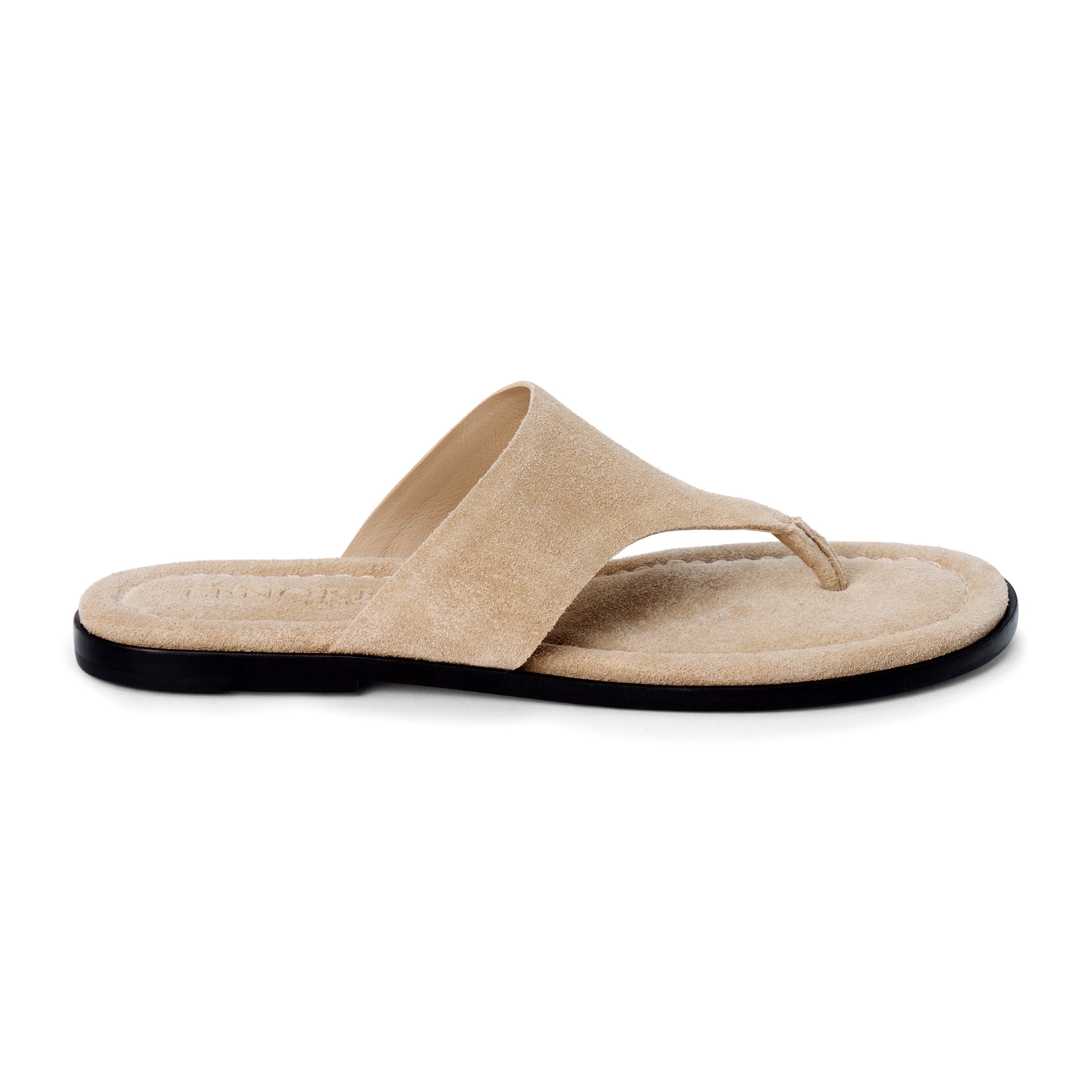 Sand beige suede flat thong sandal with wide strap and cushioned footbed, shown on a white background.