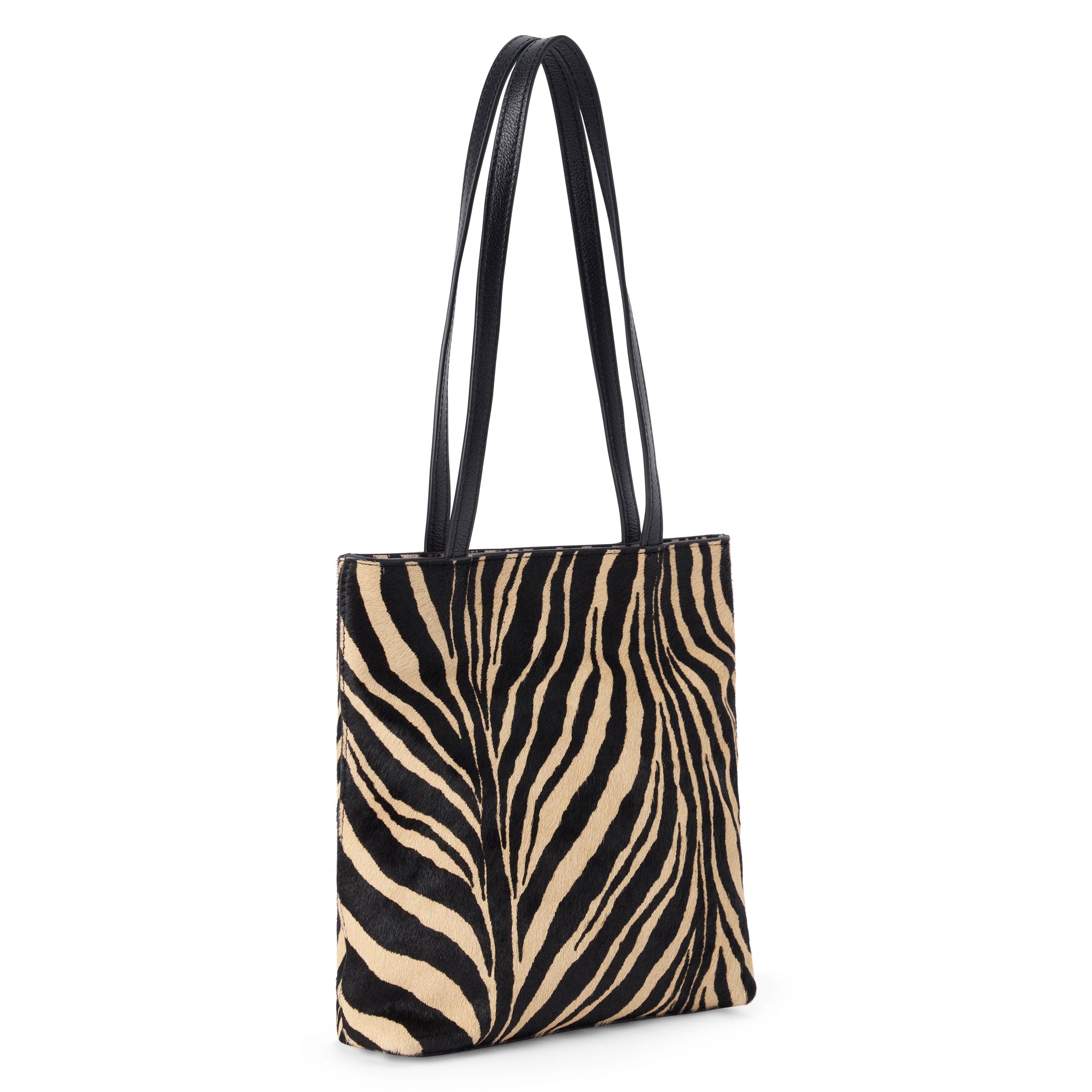 Black and tan cow hair tote bag with a zebra stripe pattern, rectangular body, and two long black shoulder straps shown on a white background.
