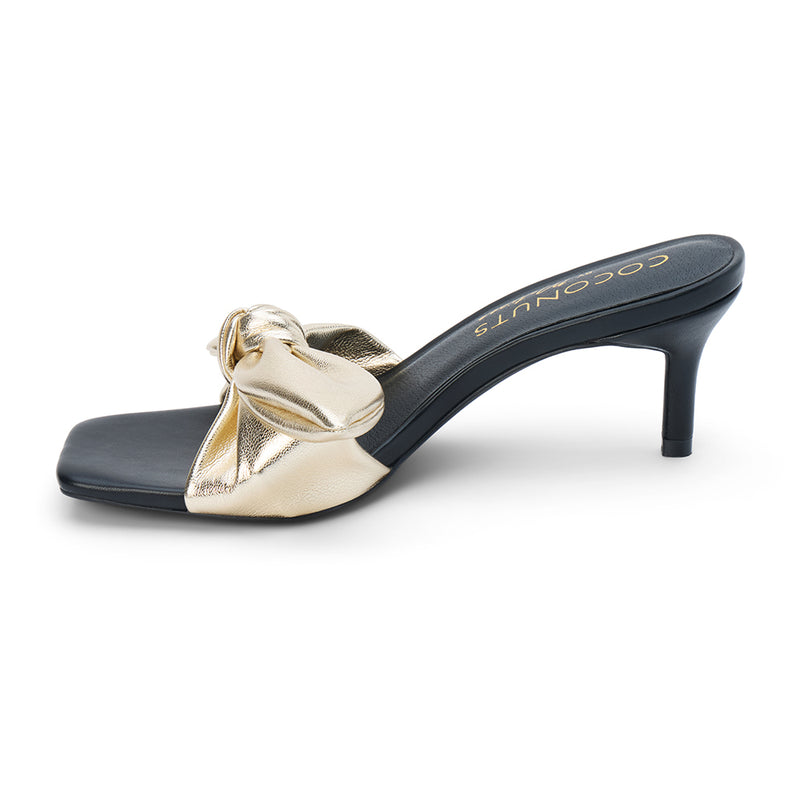 Uptown Vegan Heeled Mule – Coconuts by Matisse – Gold metallic slip-on sandal with square toe, bow detail strap, and tapered kitten heel.