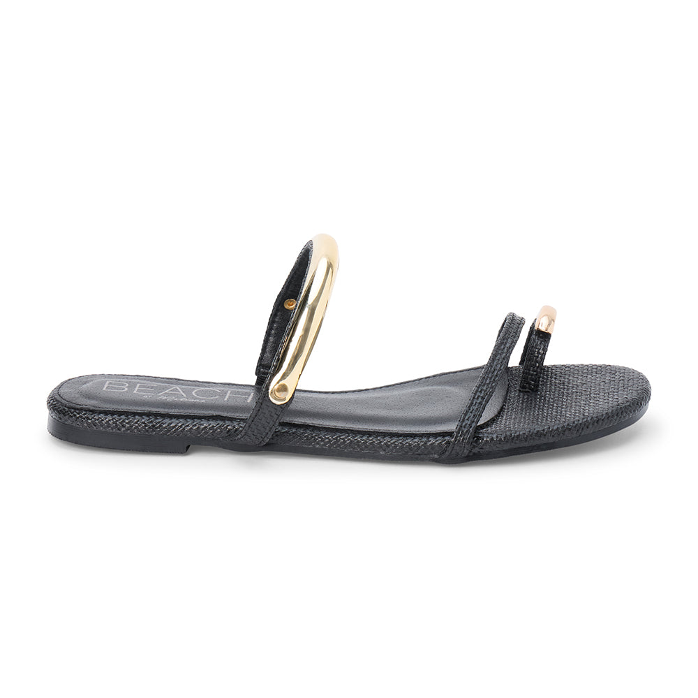 Black raffia flat sandal with slim straps and gold-tone hardware, shown on a white background.