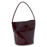 A burgundy textured leather bucket bag with a single shoulder strap and structured shape shown on a white background.