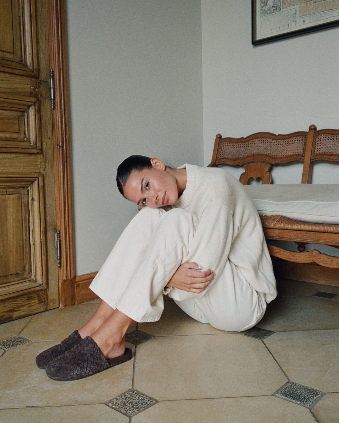 Woman sitting on the floor in a room with wooden furniture.