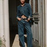 Woman wearing a denim outfit standing in a doorway.