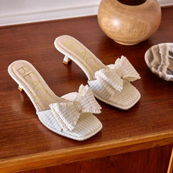 Penelope Heeled Sandal – Beach By Matisse – Cream raffia kitten heels with a flared heel and oversized layered bow detail. A playful yet polished slide for garden parties, brunches, and summer soirées.
