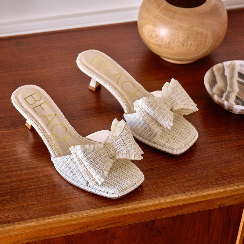 Penelope Heeled Sandal – Beach By Matisse – Cream raffia kitten heels with a flared heel and oversized layered bow detail. A playful yet polished slide for garden parties, brunches, and summer soirées.