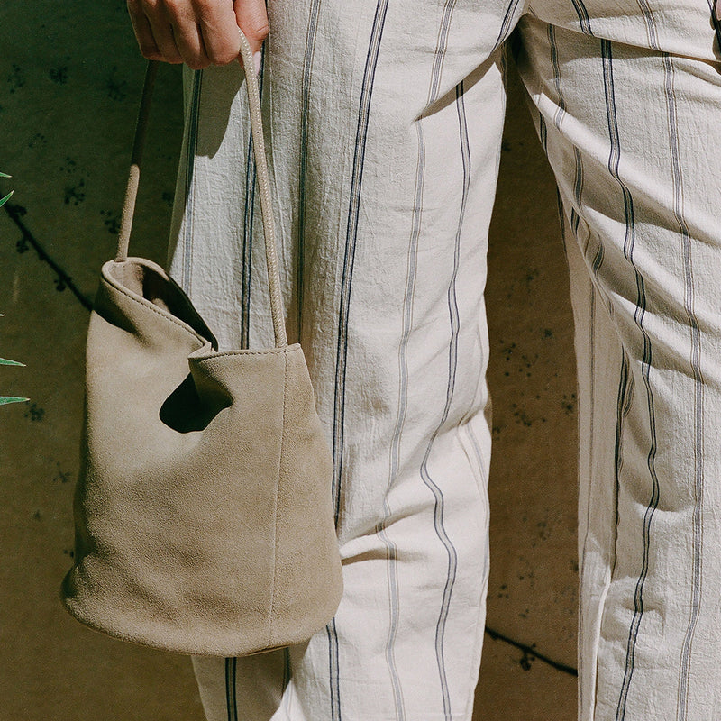 Vancouver Bucket Bag - Matisse Footwear - Minimalist bucket bag in soft beige colored suede with a seamless silhouette and a single shoulder strap. A versatile and unstructured carryall with effortless, elevated appeal.