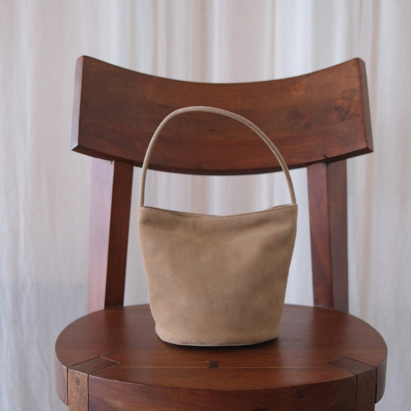 Vancouver Bucket Bag - Matisse Footwear - Minimalist bucket bag in soft beige colored suede with a seamless silhouette and a single shoulder strap. A versatile and unstructured carryall with effortless, elevated appeal.
