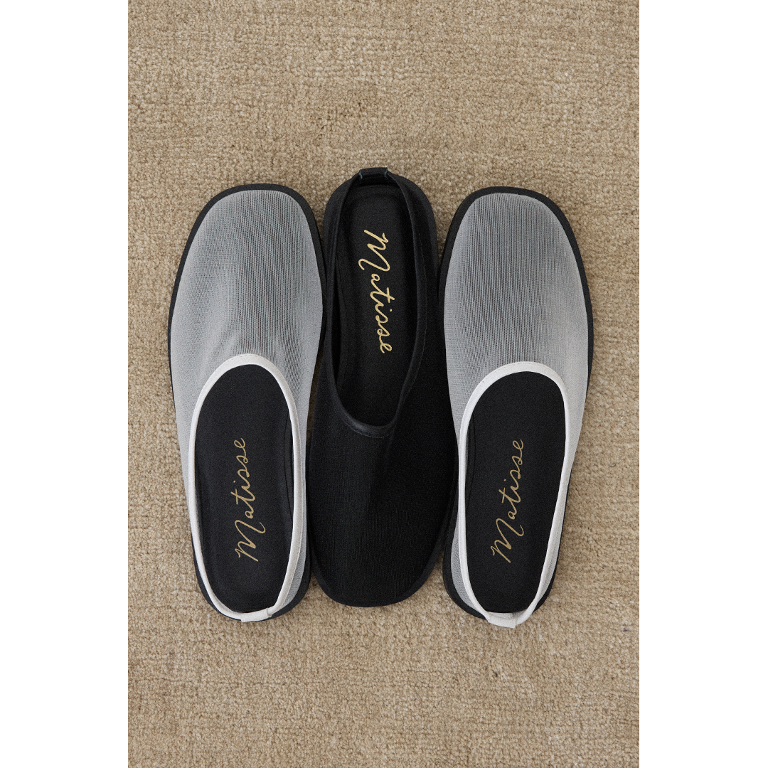 Pair of mesh slip-on shoes in white and black with 'Matisse' branding on a beige carpet.