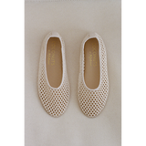 Pair of beige woven ballet flats on a light gray background.