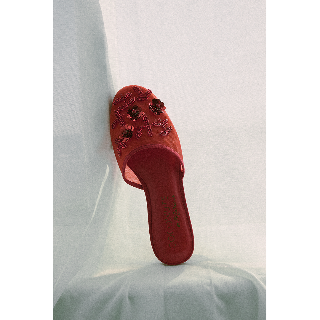 Red mesh slipper with floral embellishments on a white background.