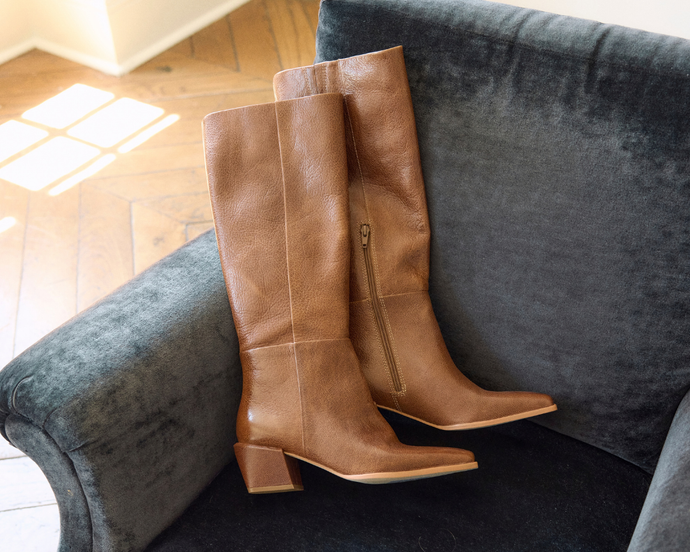 Pair of tan leather boots resting on a navy couch.