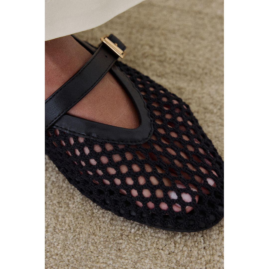 Close up shot of the black woven Nolita Ballet Flat on a beige carpet.